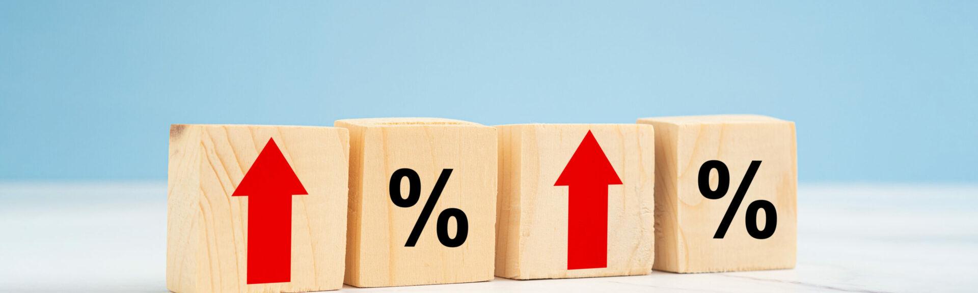 Finance and interest rate concept. Wooden cubes with arrows up and percentage symbol over a blue background. Top view. Space for text